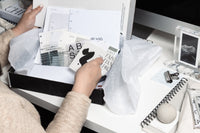 a past box with unwrapped planning and stationery items displayed.  Two hands are going through the unboxing.