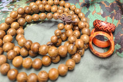 A string of wooden beads for a necklace or bracelet with three redish wooden rings beside it with different patterns on them. 