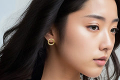 Elegant gold-plated earrings by LOKA.HAUS, displayed on a sleek model. Sustainable fashion, ethical luxury for social impact.