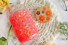 mason jar glass can snow globe cup. Inside are flower sprinkles with orange glitter. Bamboo lid with flower holographic vinyl.