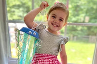 Preschooler proudly displays handmade jellyfish craft from Wiggle Worms kit, beaming with creativity and learning through play.