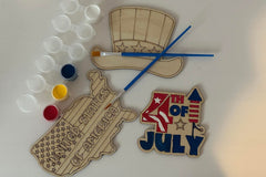 Three wooden patriotic shapes with 2 paint brushes and a paint sampler. One of the shapes is painted as an example.