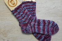 Hand Knit Socks in a Blue and Purple colorway as an example of what can be made with a skein of yarn from this box