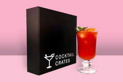 A Cocktail subscription box displaying a negroni cocktail in front of a gift box from Cocktail Crates