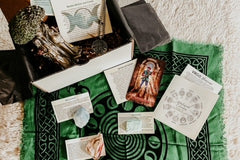 A Magickal Earth subscription box filled with scarf, crystals with informational cards, and tarot cards.