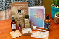 Items from a Northern Nail Polish subscription box including nail polish, cuticle pusher, a bag of granola and a planner.