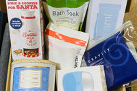 8 piece lifestyle box which includes body scrub, shampoo,,electric skincare cleaner, 3 wick candle and one weighted neck pillow, 