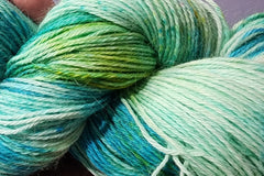 A close up of an Aqua, Teal, Turquoise, Green and Yellow skein of Hand dyed Sock Weight Baby Alpaca yarn 