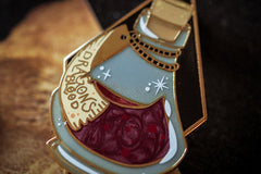 Gold plated, hard enamel pin depicting Dragon's blood in a translucent enamel bottle. Printed details and scroll, the potion is swirled.