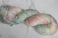 A Skein of Hand Dyed Silk Yarn in Sport Weight with pastel hues of pink, green, lavender and blues..