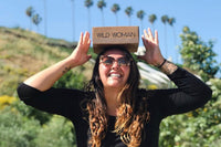 Wild Woman Box subscription boxes stacked on a mountain ledge with a scenic view in the background
