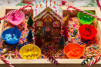 Gingerbread House theme sensory kit. rainbow colored rice, cardboard gingerbread house, candy canes, pom poms