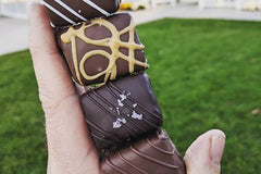 Image of a hand holding four brownie bites - Classic, Sea Salt, Peanut Butter and Espresso brownie bites.