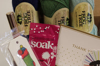 Yarn Shop Mystery Box featuring three skeins of Frog Tree Alpaca Sport yarn in green, navy, and teal with craft accessories