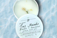 An open 2 oz tin of Jas Hands by Greenmade goods showcasing jasmine scented hand salve with dried jasmine buds.