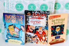 Three colorful children's books from the Kids Read Daily Book Club: "My Family and Me," "The Thrifty Guide to Ancient Rome," and "Freddie Mole, Lion Tamer"