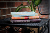 A stack of used books in front of a Used Books Monthly subscription box showcasing a book subscription service