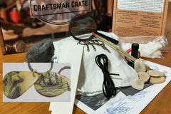 A scrimshaw kit with vegetable ivory (not an animal product), a scriber, towel, keychain, ink, and patterns.