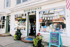 A beach scene with a subscription box from BookTIDE featuring great reads and colorful glass floats