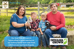 Picture of our family on our farm. Mom, Dad, and two boys sitting on hay bales holding two baby goats. 