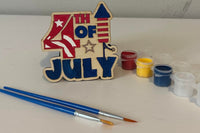 4th of July wooden shape with two paint brushes and paint sampler. The shape has been painted as an example.