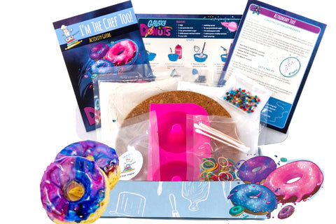 Two children engaged in the I'm The Chef Too! cooking kit, creating galaxy donuts with colorful icing and sprinkles