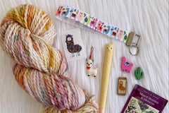 A sample of the Hand Dyed Yarn, stitch marker and extra items that will be offered in each quarterly box.