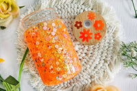 mason jar glass can snow globe cup. Inside are flower sprinkles with orange glitter. Bamboo lid with flower holographic vinyl.