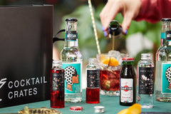 A Cocktail subscription box displaying a negroni cocktail ingredients, and a person enjoying themselves making the cocktail 