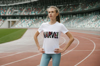 A y9oung girl preparing to run a race on a track. She is wearing workout pants and a Marvel Logo Tshirt.