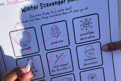 Child enthusiastically completing a recording sheet from The Activity Trunk for a winter scavenger hunt, noting various discovered items