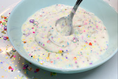 Lucky Slime already made, resting in a blue bowl with metal spoon really looks like cereal and marshmallows in milk.