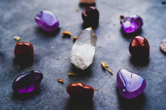grey and white table with clear pointed crystal in the middle and four red stones and 4 purple stones circled around it in a grid 