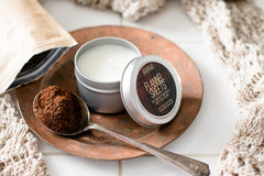 image of travel-sized candle in tin. The lid is off the candle and the label name of "Flannel Sheets" is visible. 