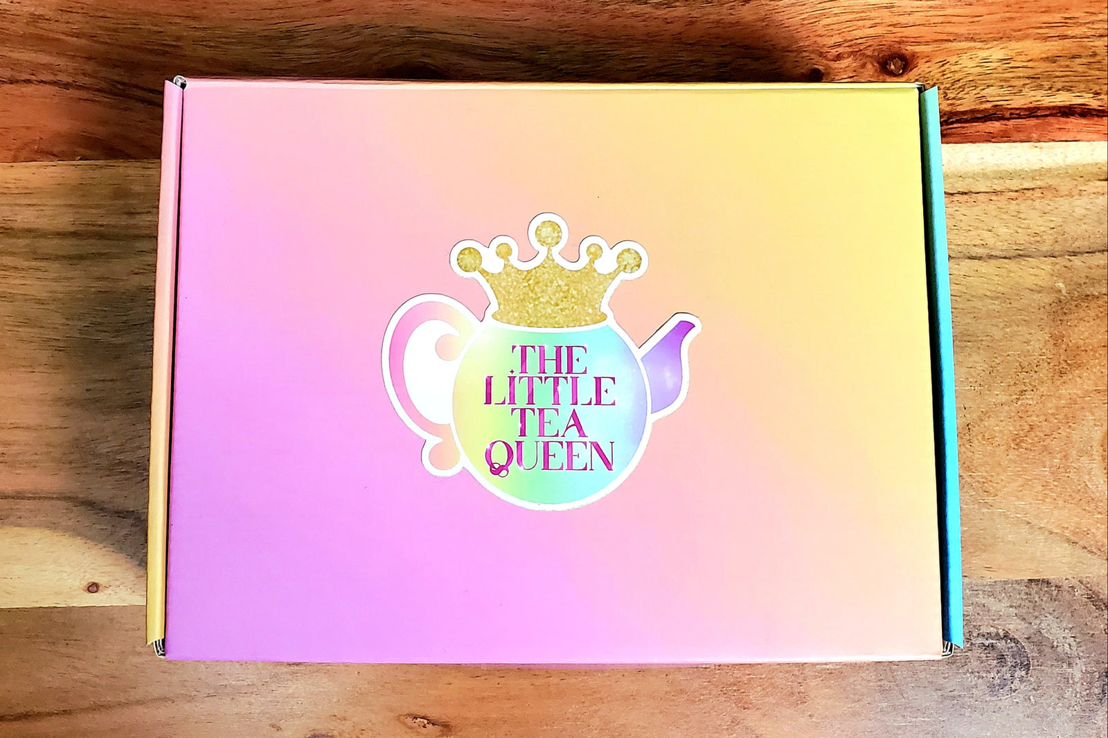 A rainbow Little Tea Box with beautiful colors that go all around it, and a sticker of my logo on top.