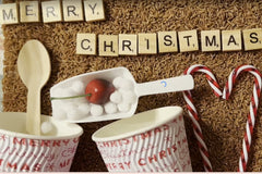 Hot Coco Themed Sensory Bin with Christmas theme . showing scrabble letters, plastic scoop, cherries, wooden spoon, hot coco cups with lid