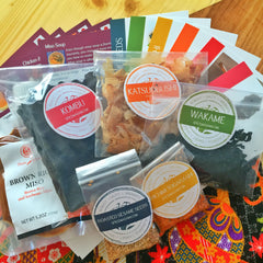 Spice Madam Monthly Subscription box featuring spice packets and recipe cards surrounded by illustrated food items