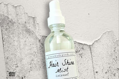 A bottle of the Coconut Hair Shine Mist by Greenmade goods with grey and white speckled concrete in the background.