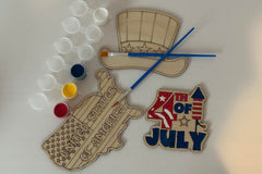 Three wooden patriotic shapes with 2 paint brushes and a paint sampler. One of the shapes is painted as an example.