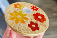 Mason jar snow globe glass can tumbler. Bamboo lid with orange and yellow holographic vinyl flowers.