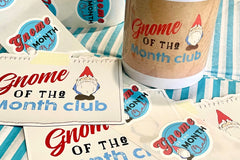 Gnome of the Month Club subscription box displayed on a front porch surrounded by neatly trimmed bushes