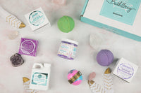 Bath Bevy Subscription box with bath bombs, bar soap, bubble bath jug, bath salts with amethyst, rose quartz and feathers