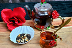 My Energy Booster tea in loose leaf form on the left and steeped on the right along with a gold spoon in the cup.