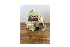 Stack of Applewood Fir Needle soap on a wooden table with white background. The soap is swirled in green, red and cream colors.