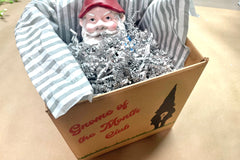 Gnome of the Month Club subscription box displayed on a front porch surrounded by neatly trimmed bushes