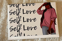 Self Love repeated on the left of the card.  Beautiful Black woman wearing blue jeans and an oversized pink sweatshirt on the right.