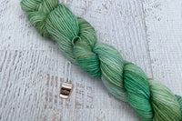 A mini Skein of Hand Dyed Merino Sock Weight Yarn and a coordinating stitch marker. Suitable for knitting and crocheting 
