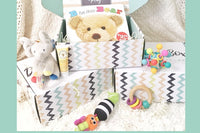 Pretty box containing touch and feel book for baby, colorful rattles, including a wooden ring rattle with wooden disks, lotion for baby. 