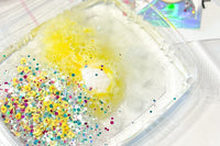 Yellow jello powder being dissolved in warm water along with the glitter and clay pieces that come with Chickadeedodah slime.