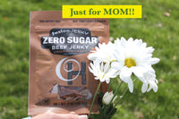 A single bag of Fusion Zero Sugar Hickory jerky.  "Just for Mom!" heading. Surrounded by grass and a bunch of white daisys.